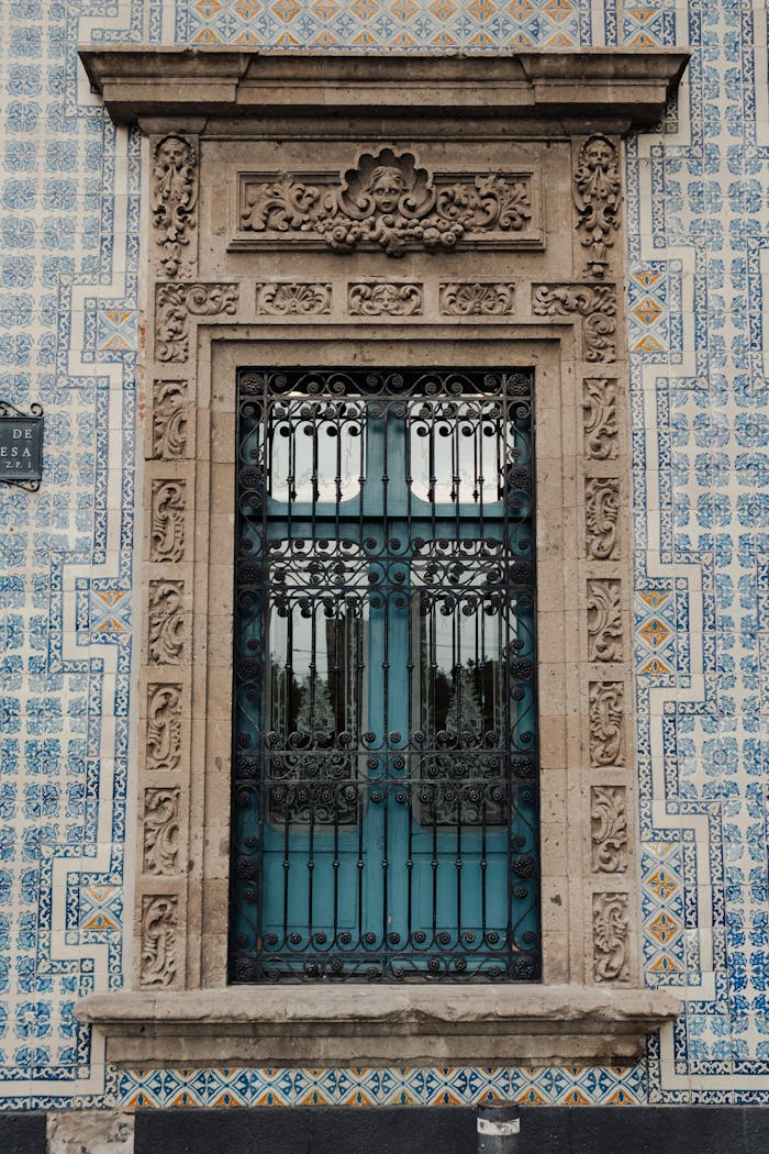Intricately designed window set in a blue patterned tile facade. A classic architectural marvel.